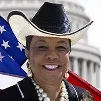 Commissisoner Wilson smiling and standing in front of the United State flag with a cowboy hat on.