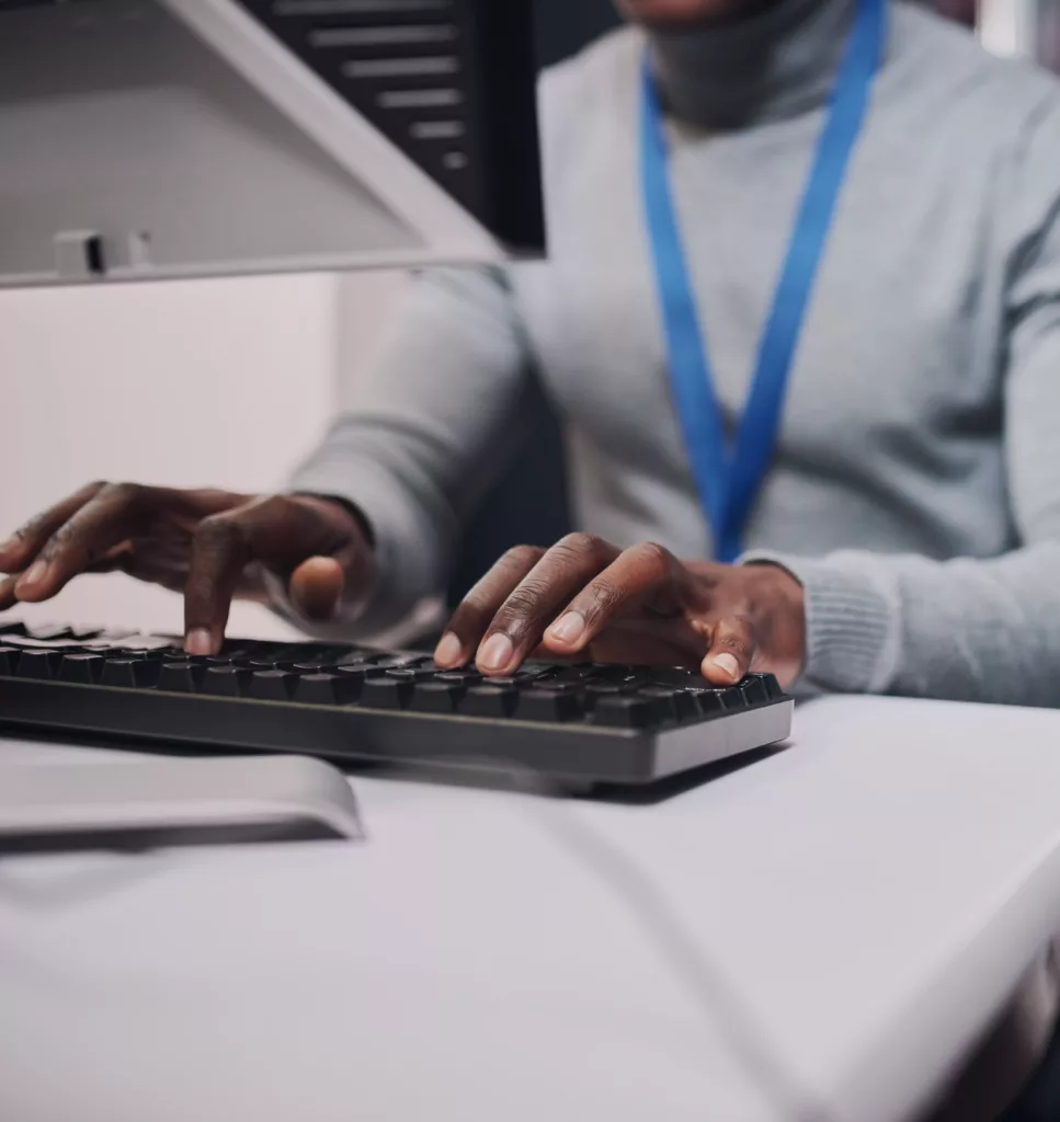 an African American man typing on a keyboard at his desk